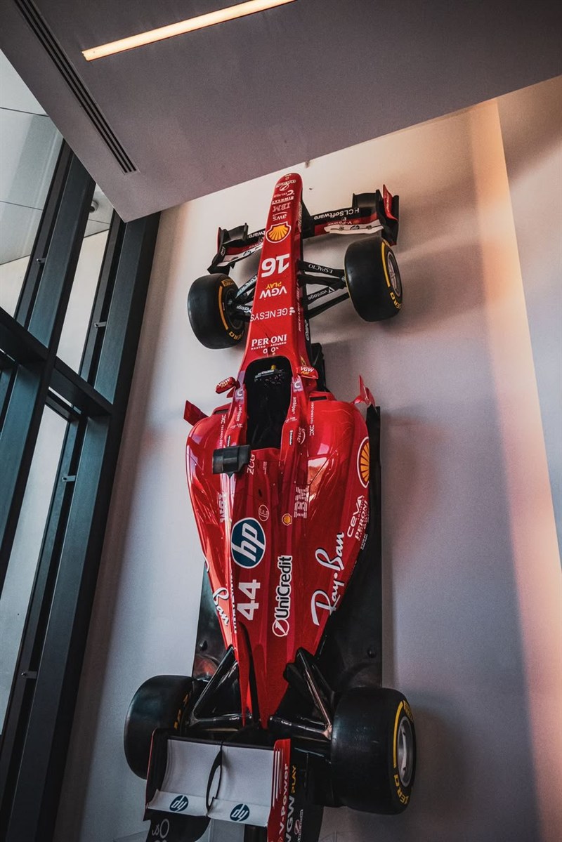 A 3D-printed Ferrari Formula 1 car mounted on a wall beside a window.